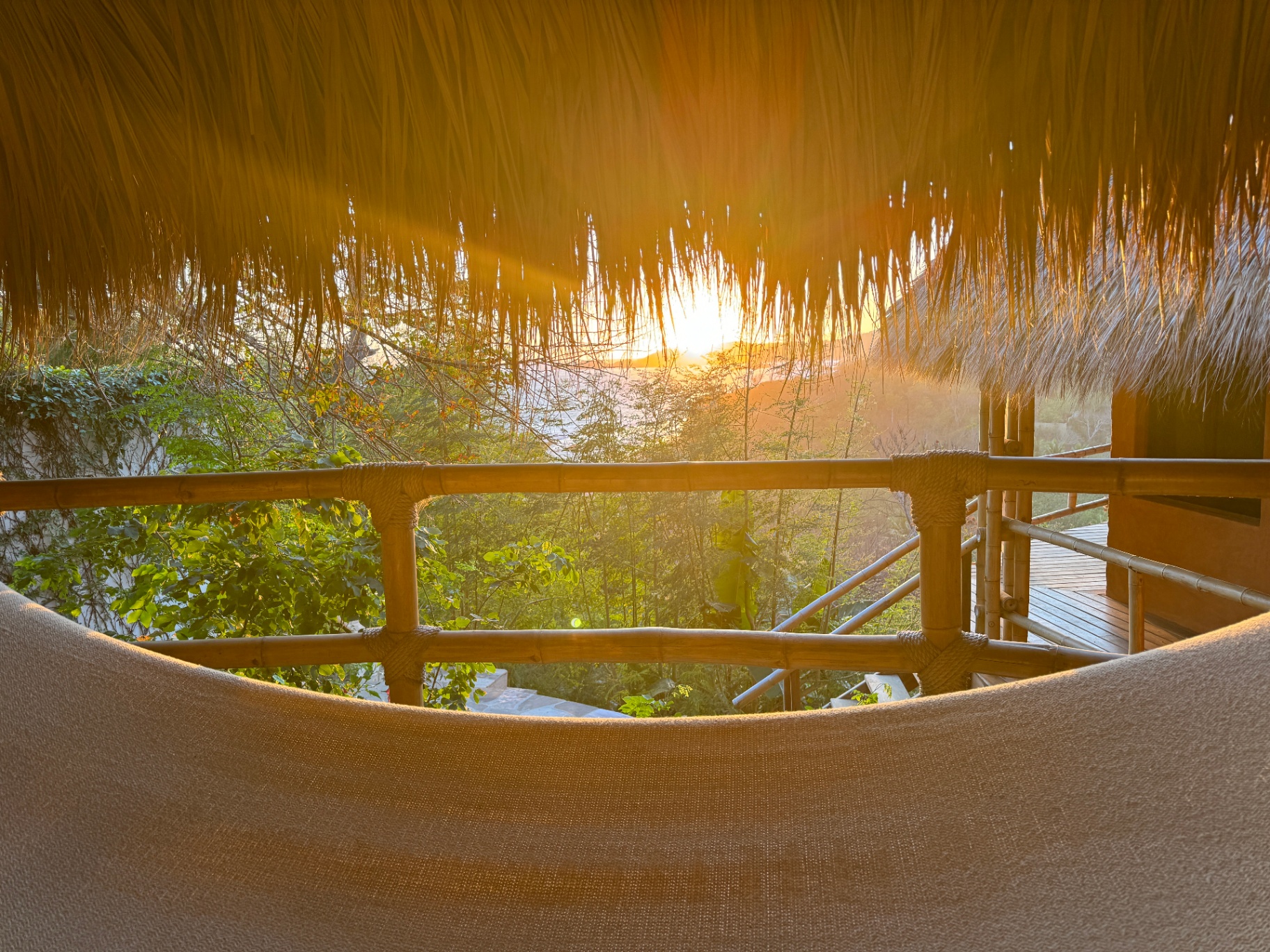 Sunset viewed from under a palapa with bamboo railing